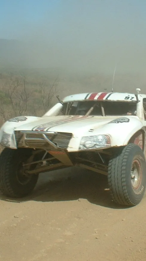 SCORE Trophy Truck racing down a dusty dirt road in Baja California
