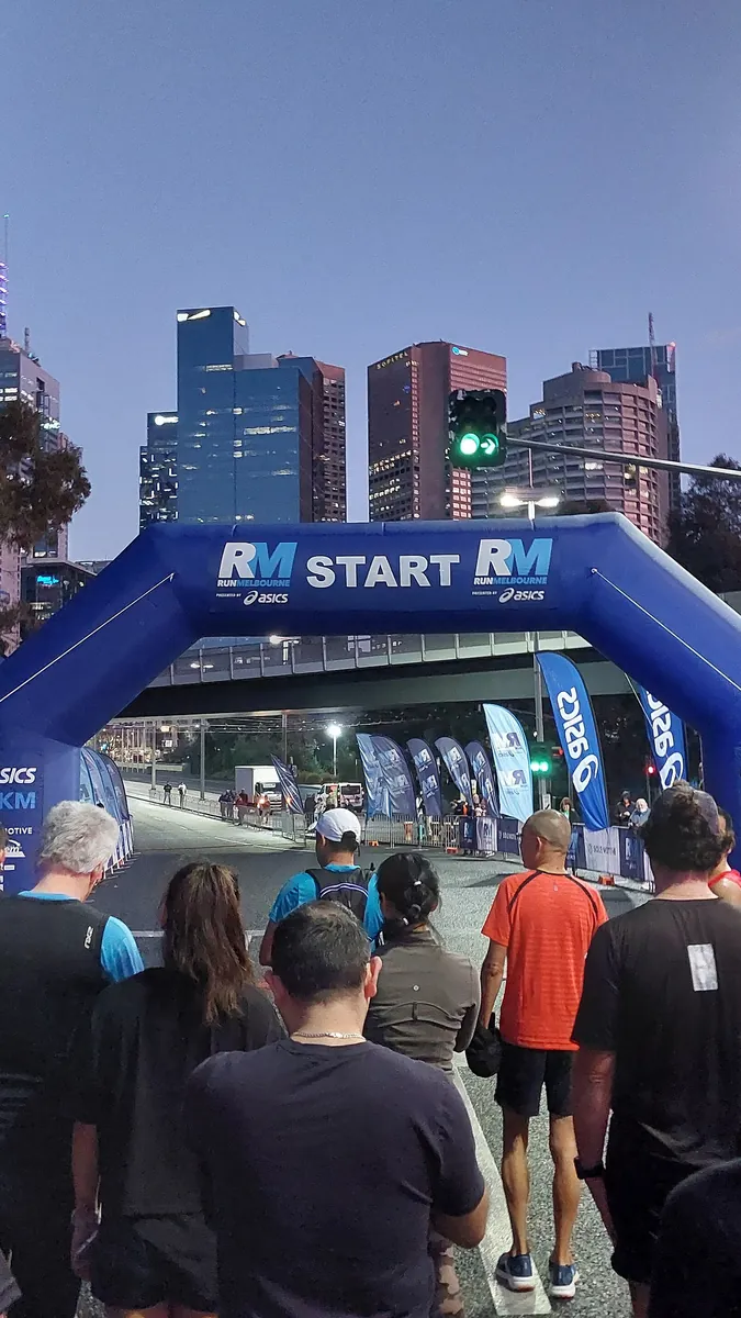 Runners gathered under the inflatable arch at the start line of a half marathon at dusk