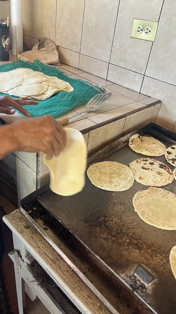 A cook turning handmade flour tortillas on a griddle
