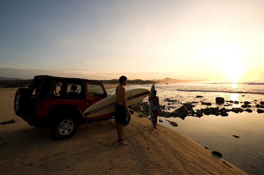Surfers and a jeep on the beach at sunset at Costa Azul, San José del Cabo